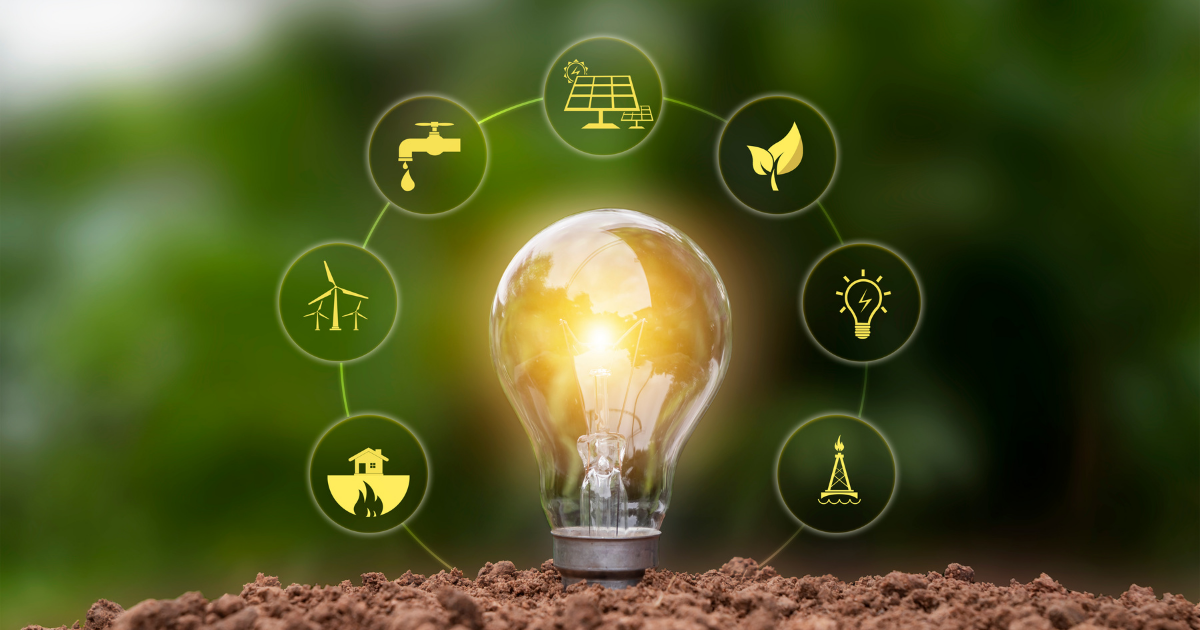 Eine leuchtende Glühbirne steht auf Erde, umgeben von kreisförmigen Symbolen zu erneuerbaren Energien wie Solarenergie, Windkraft, Wassernutzung und nachhaltigen Ressourcen, vor einem grünen Naturhintergrund.