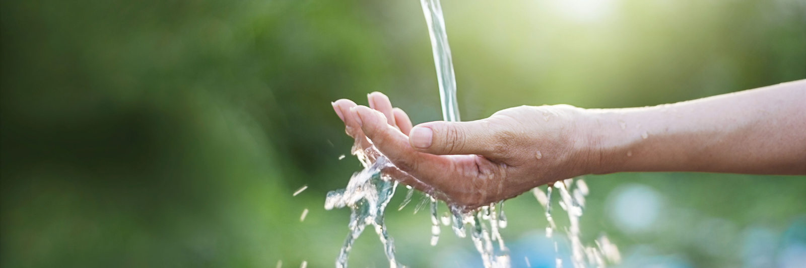 Nahaufnahme einer ausgestreckten Hand, über die klares Wasser fließt.