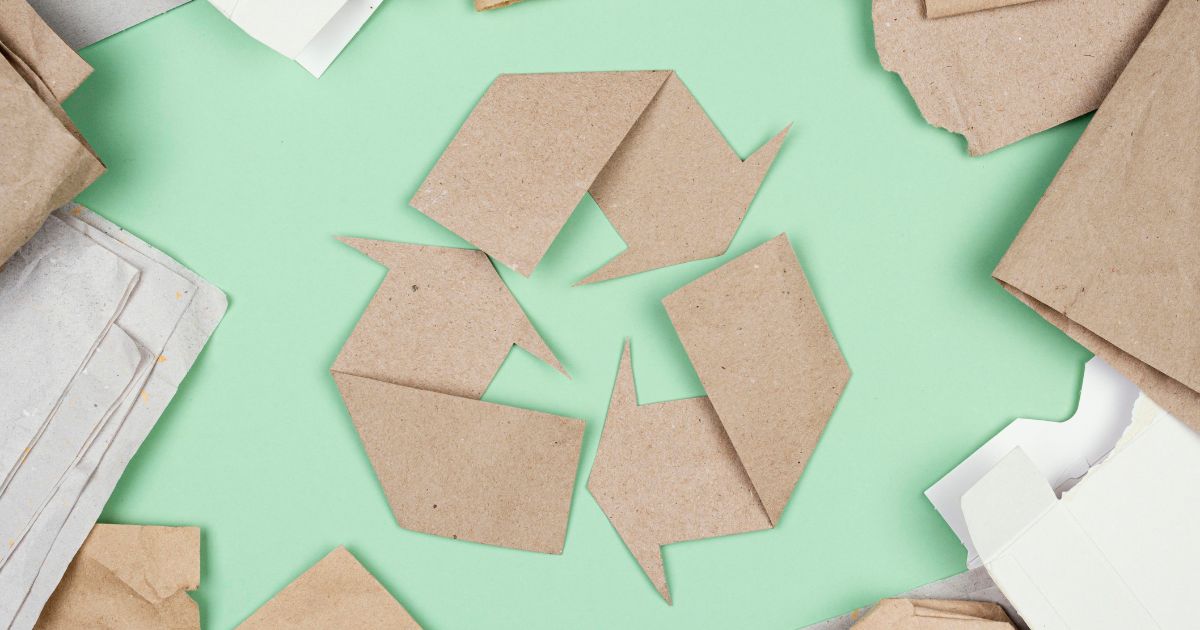 Pappkarton in Recycling-Form auf grünem Untergrund