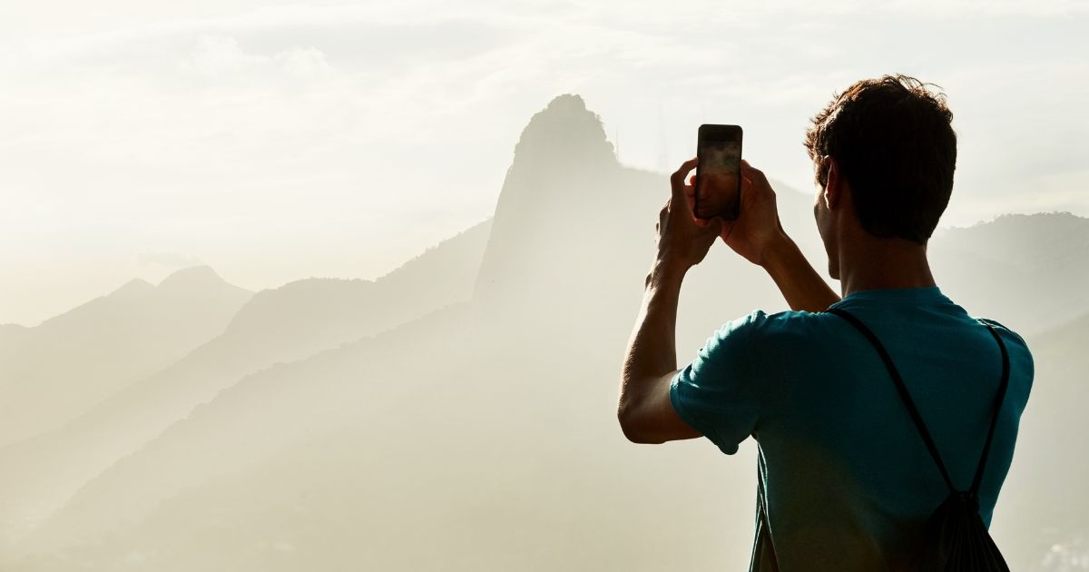 Mann fotografiert die Landschaft mit Smartphone