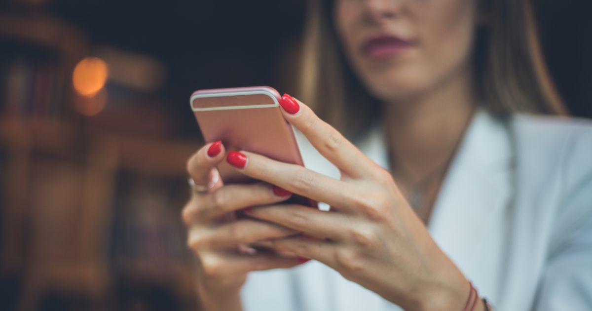Frau hält rosa Handy in der Hand