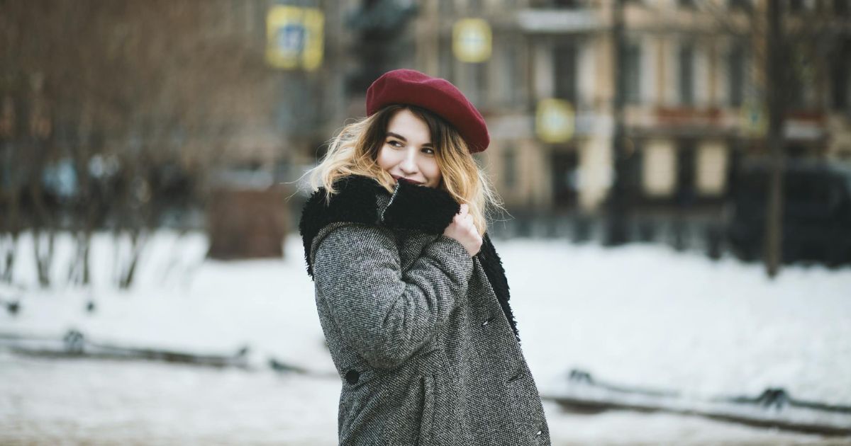 Frau mit Mantel und Mütze läuft durch die Stadt im Winter