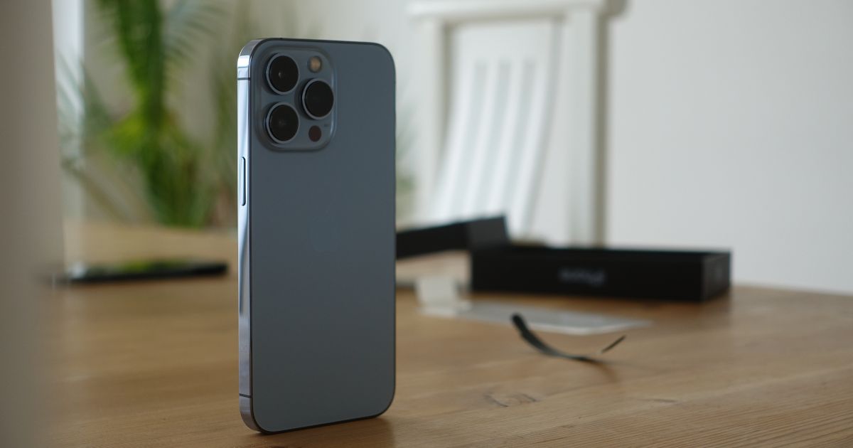 iPhone steht auf Tisch, dahinter Stuhl und Pflanze