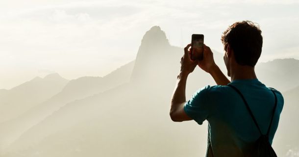Mann fotografiert die Landschaft mit Smartphone